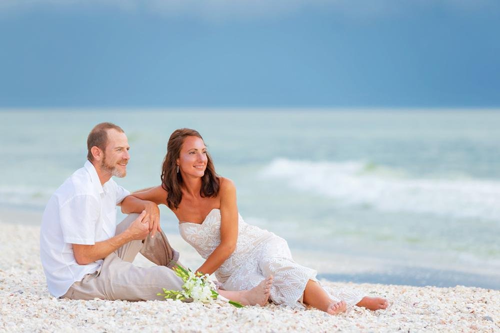 newlyweds sit on Captiva Island beach after ceremony